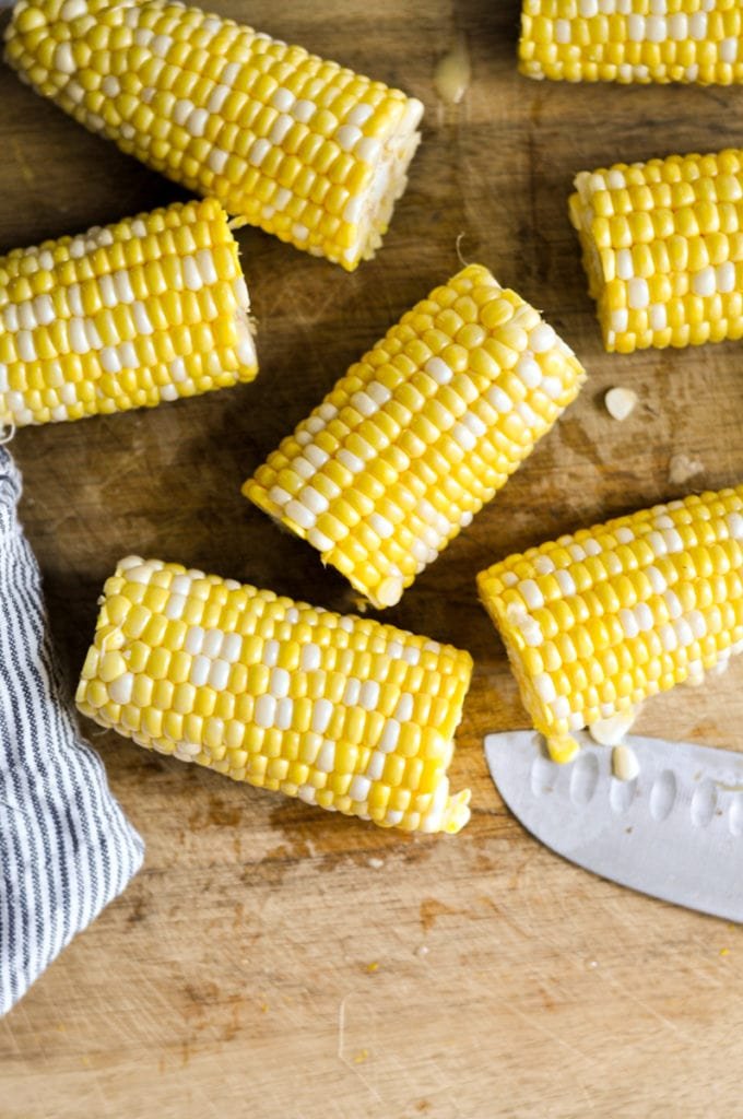 Three ears of corn cut in half on a cutting board