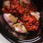 Raw chicken, salsa, and taco seasonings in a slow cooker ready to start cooking