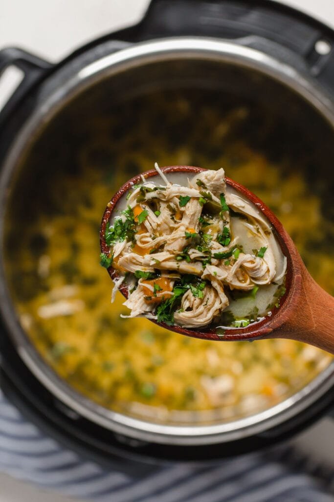 A wooden spoon serving up a crockpot Whole30 white chicken chili.